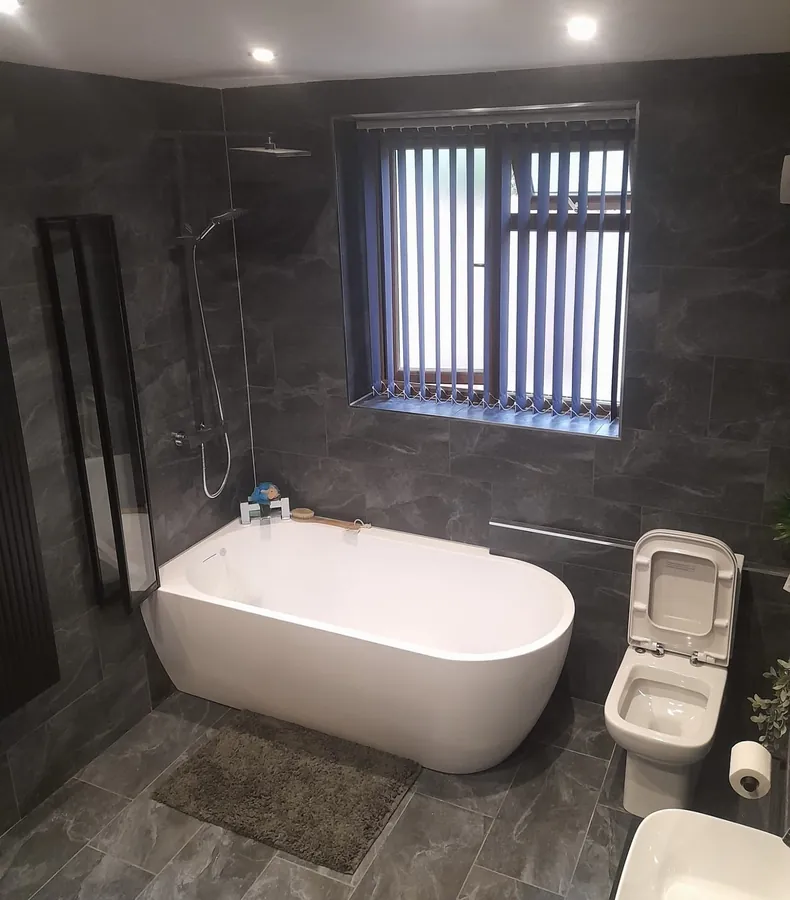 Dark tiled bathroom with freestanding bath